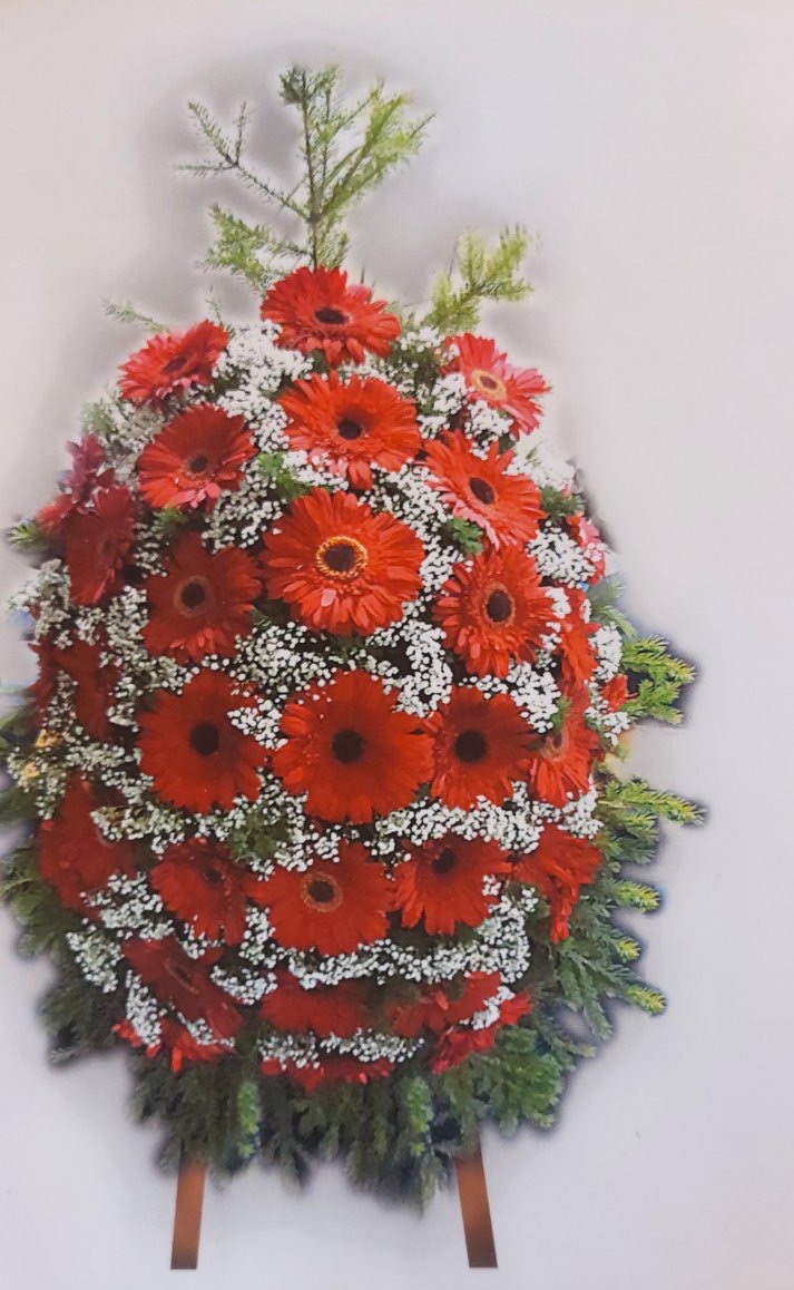 Траурен венец с кремави и розови рози, бели цветя и зеленина, поставен на стойка